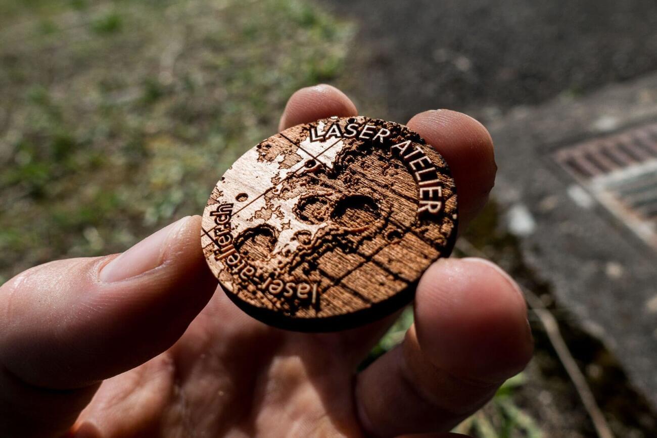 Laser engraved token made from cherry wood. It shows a small section of moon topography.